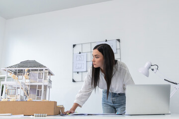 Portrait of Young beautiful caucasian architect focus on comparing house structure between house...