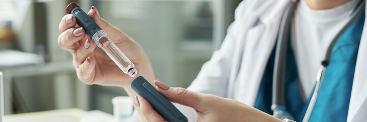 Caucasian female doctor holding insulin pen and glucometer preparing for diabetes consultation in...