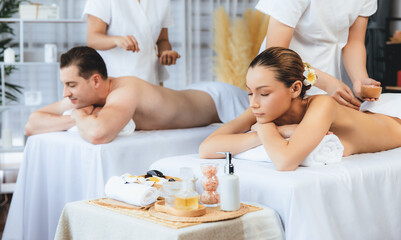 Blissful couple customer having exfoliation treatment in luxury spa salon with warmth candle light...