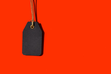 Blank black tag isolated on red background with copy space. Template Mock up