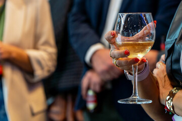 Close up of female hand supporting a wineglass with white wine on a party