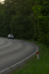 A solitary car is making its way down a winding and curvy road that snakes through the peaceful...