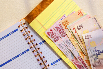Turkish lira banknotes are placed beside planner, showcasing moment of organization finance in workspace.