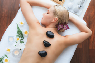 Hot stone massage at spa salon in luxury resort with day light serenity ambient, blissful woman...