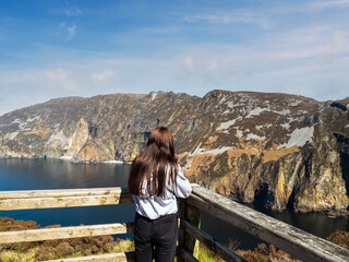 Teenager girl sightseeing stunning Slieve League cliff nature scenery and Atlantic ocean. Blue...
