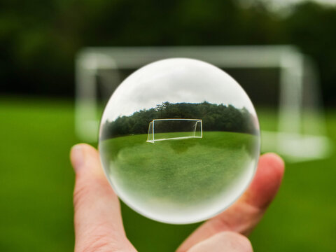 Football or soccer goal posts in glass ball which is hold by a someone hand. Forecasting sport results in popular world sport. Betting on club and national teams concept. Selective focus.