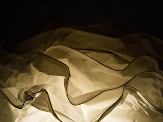 Artistic paper-like structure illuminated by warm inner light. Layered forms cast soft shadows on a...