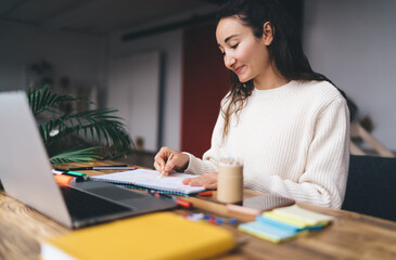 Young woman working remotely with laptop and colored graph, drawing strategy outlines, representing...