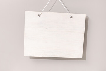 Blank white wooden sign hanging on beige background. Mock up template