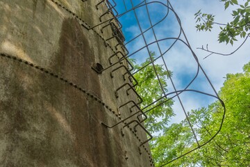 A rusty ladder with a fence on the wall of a steel water tower on a sunny summer day