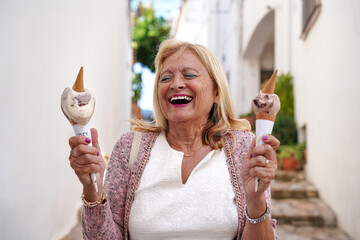 Happy senior woman enjoying two ice creams in summer.