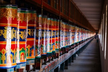 Colorful prayer wheels line a corridor at Kirti Monastery in Ngawa, showcasing Tibetan Buddhist...