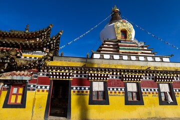 Colorful Dudul Chorten at Kirti Monastery in Ngawa, historic Amdo region, featuring traditional Tibetan stupa architecture with vibrant yellow and red monastery walls.