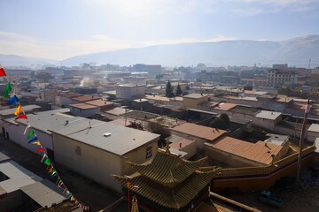 Panoramic view of Kirti Monastery and surrounding Tibetan townscape in Ngawa, historical Amdo region of Tibet, with traditional rooftops and distant mountains in soft morning light.