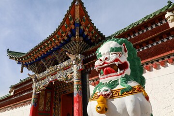 Colorful snow lion statue guards the entrance of Labrang Monastery, a major Tibetan Buddhist site in the Amdo region of Gansu, showcasing intricate architectural detail.

