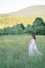 Pregnant woman holds her hands on her belly, walking in the field in anticipation of the baby....
