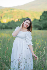 Pregnant woman holds her hands on her belly, walking in the field in anticipation of the baby....