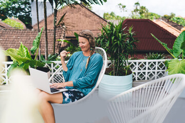 Freelance woman working and snacking while using laptop outdoors, illustrating balance between...