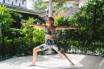 Confident woman holding warrior II pose outdoors, embodying focus, spatial awareness and strength...