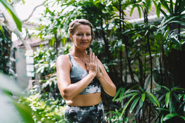 Mindful woman practicing tree pose with closed eyes, focusing inward and eliminating distraction,...