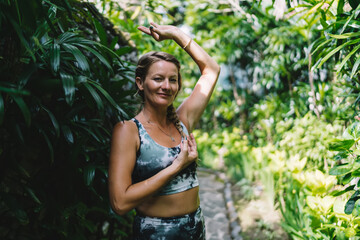 Woman with eyes closed and hand on heart, gently raising one arm in tranquil gesture, symbolizing...