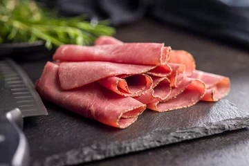 Gardinen Sliced beef pastrami on cutting board on black table. © Jiri Hera
