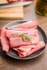Sliced beef pastrami on plate on wooden table.