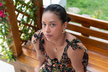 Fashion model posing on wooden bench in tropical garden