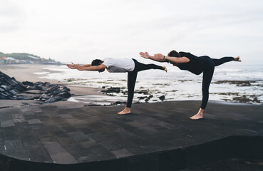 Two men in mirrored balance yoga pose, floating on one leg, symbolizing trust, body intelligence...