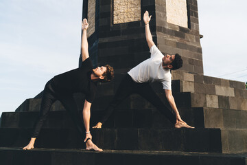 Focused men practicing Trikonasana on monument steps, merging architectural balance with mindful...