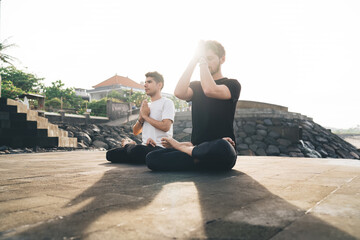 Male duo meditating with hands in prayer near the forehead, capturing the moment of silent...