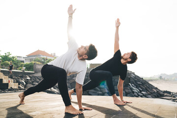 Two male yogis in lunge twist raise arms with focus, embodying physical alignment and mental...