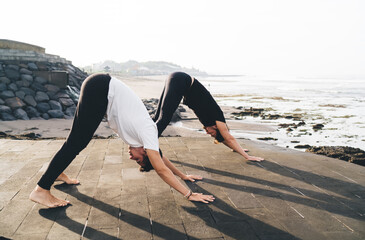 Two men in aligned downward dog form emphasize digital grounding and symmetry, symbolizing control...