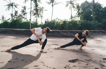 Two men mirror prayer twists in deep lunges—embodying symmetry, breath focus, and inner...