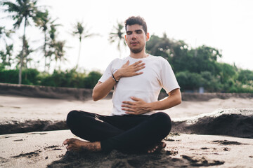 Young man uses deep diaphragm breathing to regulate and disconnect—inner stillness cultivated against background of always-on tech culture.