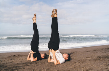 Synchronized shoulder stand on beach represents strength and discipline—embodied reboot for mind...