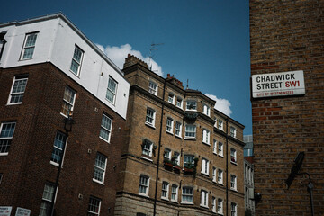 Fototapeta premium Chadwick Street, London Architecture: A captivating view of traditional London architecture, showcasing a blend of brick and stucco buildings under a vibrant blue sky.