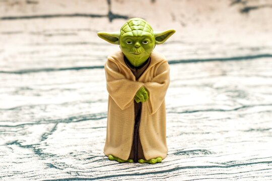 A detailed green Yoda figure stands on a textured surface,