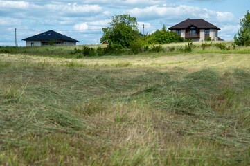 In a tranquil countryside, workers are busy with haymaking, while two houses sit peacefully under a...