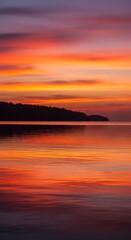Fototapeta premium Vibrant sunset paints the sky and reflects beautifully on calm water.