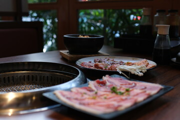 Chinese spicy hotpot soup. Plate with raw meat slides of beef at the table in a restaurant. Typical...