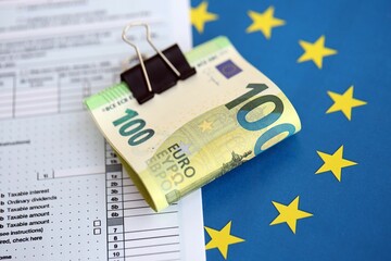European euro currency money notes bunch on tax form and European union blue flag close up