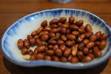 Peanuts ceramic bowl Close up of crunchy roasted Peanuts Indian namkeen (snacks) on a ceramic white bowl. Top view
