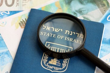 Israel New Shekels banknotes and passport with loupe. The current Israel money bills and pass