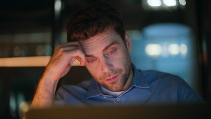 Closeup tired manager looking laptop at dark office. Overworked freelancer