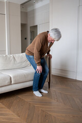 Senior man cries out painfully attempting to stand with degenerative knee joint destruction. Bone on bone friction, synovial fluid loss, chronic inflammation, untreated osteoarthritis progress