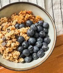 Healthy breakfast bowl with granola and fresh blueberries served on a wooden table