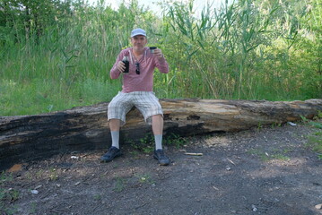 Middle-aged man in the forest walking walking tourist in checkered shorts and white cap walking slowly breathing air