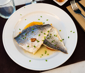 Piece of fried dorado with side dish of baked potato is served on plate. fish and side dish serving option.