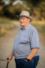 Grandfather in a hat. Portrait of a very old Caucasian man. Portrait: elderly, lonely, elderly, with many wrinkles on his face. Close-up of a thoughtful old man standing alone outdoors.